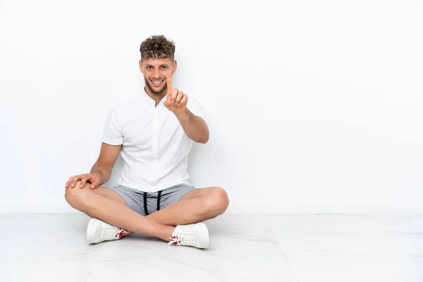 Young Blonde Man Sitting Floor Isolated White Background Showing Lifting — 스톡 사진