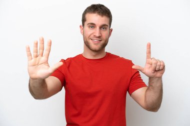 Beyaz arka planda izole edilmiş genç beyaz adam yediyi parmaklarıyla sayıyor