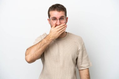 Beyaz arka planda izole edilmiş beyaz tenli genç bir adam ağızı eliyle kapatıyor.