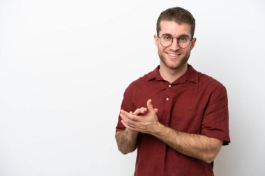 Beyaz arka planda izole edilmiş genç beyaz adam alkışlıyor.