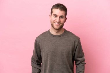 Pembe arka planda izole edilmiş genç beyaz adam gülüyor.