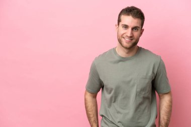 Pembe arka planda izole edilmiş genç beyaz adam gülüyor.
