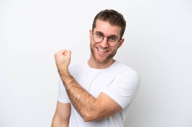 Young caucasian man isolated on white background With glasses and celebrating a victory