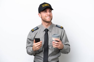 Young safeguard caucasian man isolated on white background holding coffee to take away and a mobile while thinking something