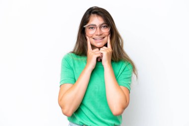 Beyaz arka planda izole edilmiş genç beyaz kadın mutlu ve hoş bir ifadeyle gülümsüyor.