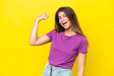 Sarı arka planda izole edilmiş beyaz bir kadın güçlü bir jest yapıyor.