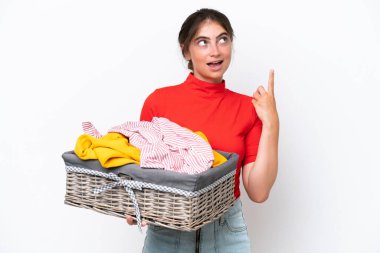 Young caucasian woman holding a clothes basket isolated on white background thinking an idea pointing the finger up