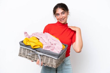 Young caucasian woman holding a clothes basket isolated on white background laughing