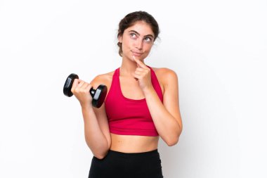 Young sport caucasian woman making weightlifting isolated on white background having doubts and thinking