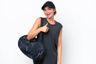 Spor çantalı genç bayan beyaz arka planda izole edilmiş bir şekilde baş parmak hareketi yapıyor.