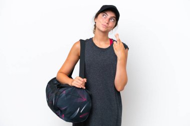 Spor çantalı genç bayan beyaz arka planda izole edilmiş, parmakları çapraz ve en iyisini diliyor.