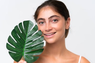 Beyaz arka planda izole edilmiş beyaz bir kadın elinde mutlu bir ifadeyle bir palmiye yaprağı tutuyor. Portreyi kapat