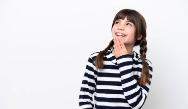 Beyaz arka planda izole edilmiş küçük beyaz kız gülümserken yukarı bakıyor.