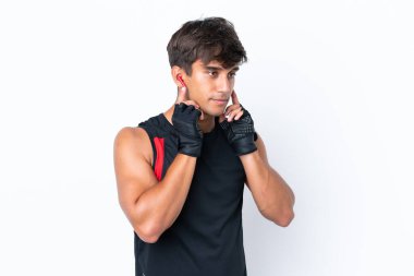 Beyaz arka planda izole edilmiş genç beyaz adam müzik dinliyor.