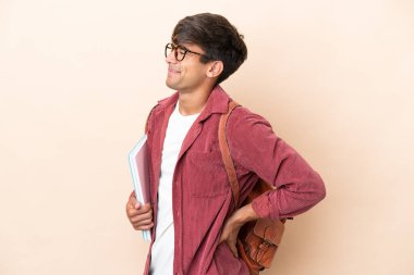 Young student caucasian man isolated on ocher background suffering from backache for having made an effort