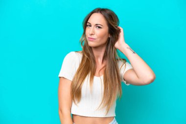 Kafkasyalı genç bir kadın mavi arka planda izole edilmiş. Şüpheleri var.