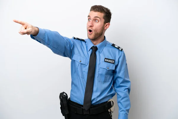 Young police caucasian man isolated on white background pointing away