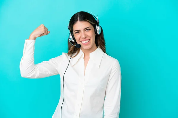 Telemarketer Italian woman working with a headset isolated on blue background doing strong gesture