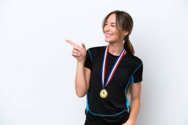 Beyaz arka planda madalyaları olan beyaz saçlı genç bir kadın parmak göstererek bir ürün sunuyor.