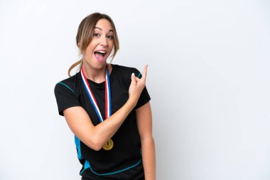 Beyaz arka planda izole edilmiş madalyalı beyaz bir kadın şaşırmış ve işaret ediyor.