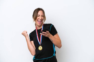 Beyaz arka planda madalyaları olan beyaz saçlı genç beyaz bir kadın ve telefon zafer pozisyonunda.