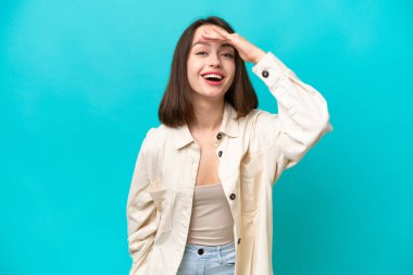 Genç Ukraynalı bir kadın mavi arka planda izole edilmiş. Bir şeye bakmak için uzaklara bakıyor.