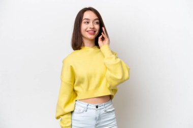 Beyaz arka planda izole edilmiş genç Ukraynalı kadın cep telefonuyla sohbet ediyor.