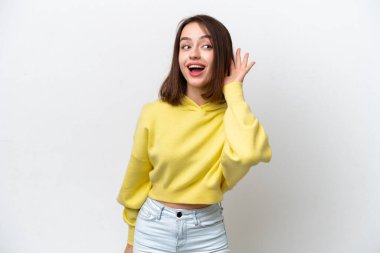 Genç Ukraynalı bir kadın beyaz arka planda izole edilmiş bir şekilde elini kulağına koyarak bir şeyler dinliyor.