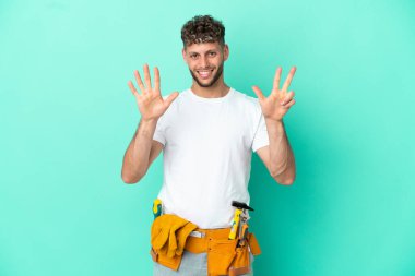 Genç elektrikçi sarışın adam yeşil arka planda izole edilmiş. Sekiz parmaklı sayıyor.