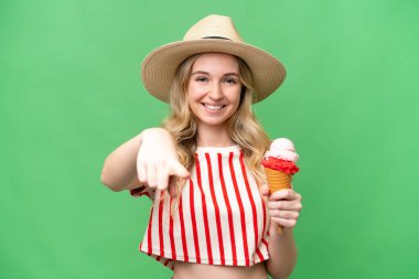 Young English woman with a cornet ice cream over isolated background points finger at you with a confident expression