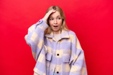 Young English woman isolated on red background doing surprise gesture while looking to the side
