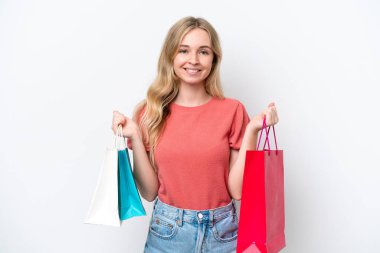 Beyaz arka planda izole edilmiş genç bir İngiliz kadın alışveriş torbaları tutuyor ve gülümsüyor.