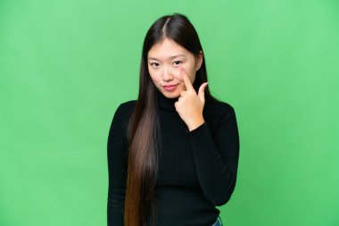 Young Asian woman over isolated chroma key background showing something