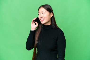Genç Asyalı kadın izole edilmiş krom anahtar geçmişi olan biriyle cep telefonu konuşmasını sürdürüyor.