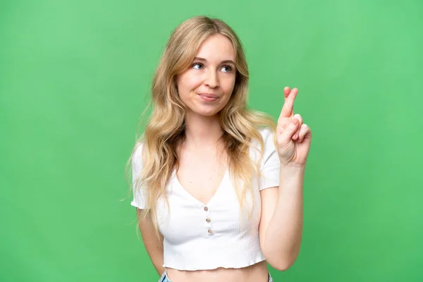 Young English woman over isolated background with fingers crossing and wishing the best