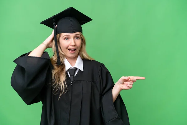 Young university English graduate woman over isolated background surprised and pointing finger to the side
