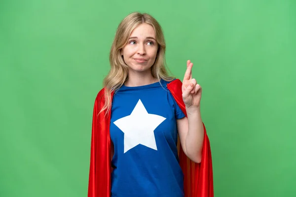 Super Hero English woman over isolated background with fingers crossing and wishing the best