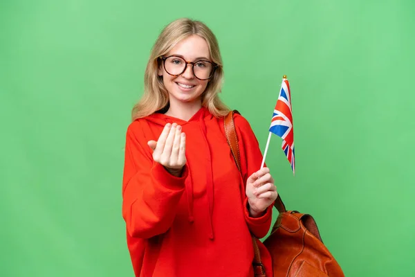Young hispanic woman holding an United Kingdom flag over isolated background inviting to come with hand. Happy that you came