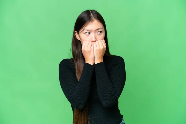 Young Asian woman over isolated chroma key background nervous and scared putting hands to mouth