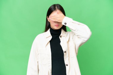 Young Asian woman over isolated chroma key background covering eyes by hands. Do not want to see something