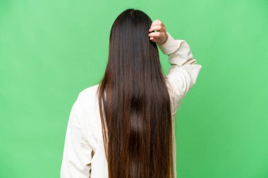 Young Asian woman over isolated chroma key background in back position and thinking