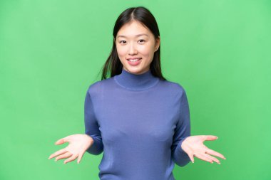 Genç Asyalı kadın izole edilmiş krom anahtar arka planda mutlu ve gülümsüyor