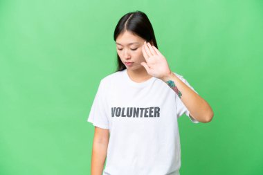 Young volunteer woman over isolated chroma key background making stop gesture and disappointed