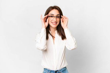 Gözlüklü ve şaşırmış beyaz arka planı olan beyaz tenli genç bir kadın.