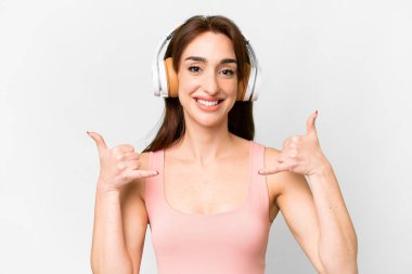 Young caucasian woman over isolated white background listening music making rock gesture