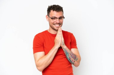 Beyaz arka planda izole edilmiş beyaz, yakışıklı genç bir adam avuç içlerini bir arada tutuyor. İnsan bir şey ister.