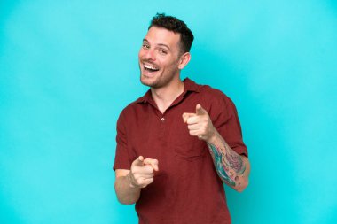 Genç, beyaz, yakışıklı, mavi arka planda soyutlanmış ve gülümseyen bir adam.