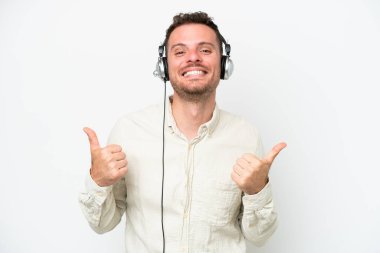 Tele pazarlamacı, beyaz arka planda izole edilmiş kulaklıkla çalışan beyaz bir adam. Baş parmak hareketleriyle ve gülümsemesiyle.