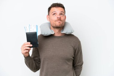 Young caucasian man holding a passport isolated on white background and looking up