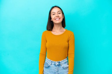 Mavi arka planda izole edilmiş genç beyaz kadın gülüyor.